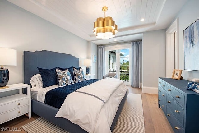 bedroom with access to exterior, a raised ceiling, a chandelier, and light hardwood / wood-style flooring