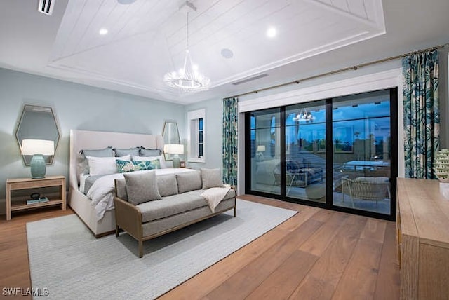 bedroom featuring access to outside, a raised ceiling, a chandelier, and light wood-type flooring