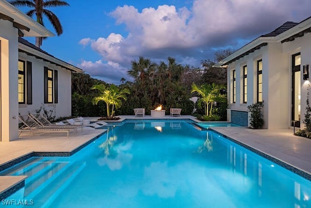 pool at dusk featuring a patio area