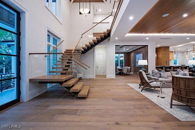 foyer with a notable chandelier, wood-type flooring, and a towering ceiling