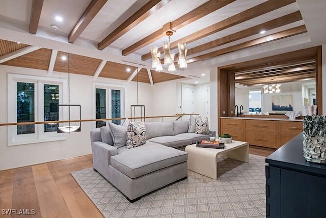 living room featuring beam ceiling, light hardwood / wood-style floors, a healthy amount of sunlight, and sink