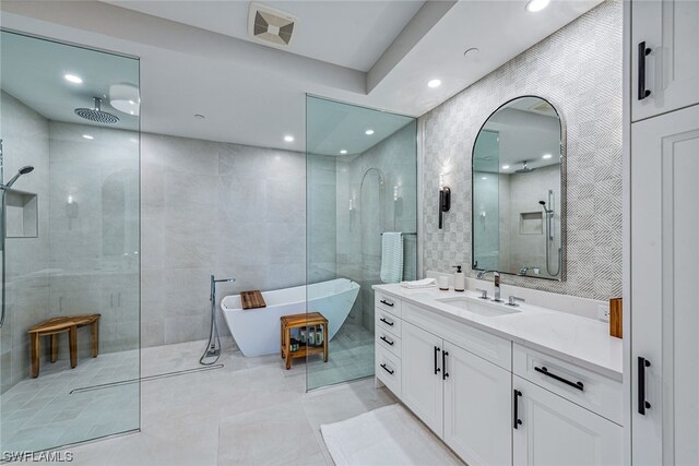 bathroom featuring tile walls, a bath to relax in, vanity with extensive cabinet space, and tile flooring