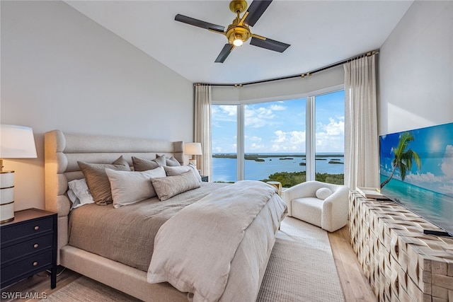 bedroom with a water view, access to exterior, ceiling fan, and light wood-type flooring