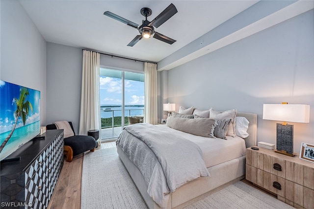 bedroom featuring light hardwood / wood-style flooring, a water view, access to exterior, and ceiling fan