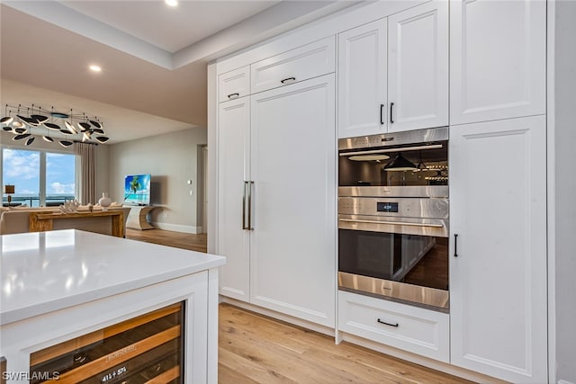 kitchen featuring light hardwood / wood-style flooring, double oven, and white cabinetry