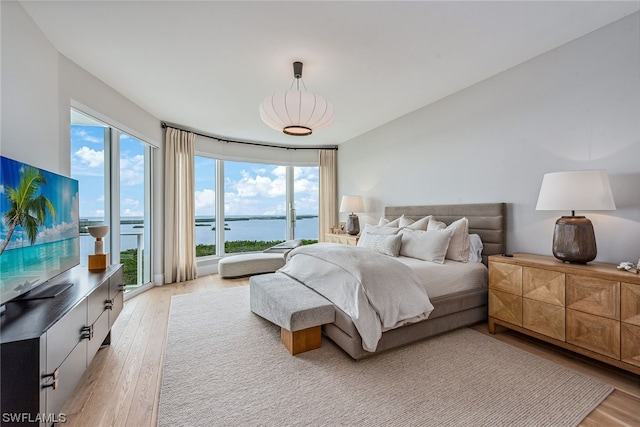 bedroom featuring light wood-type flooring and a water view