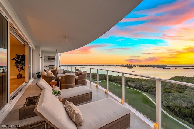 balcony at dusk featuring an outdoor hangout area and a water view