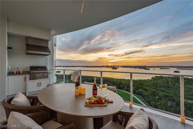 balcony at dusk with a water view and grilling area