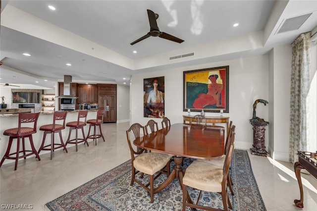 tiled dining room with a tray ceiling and ceiling fan