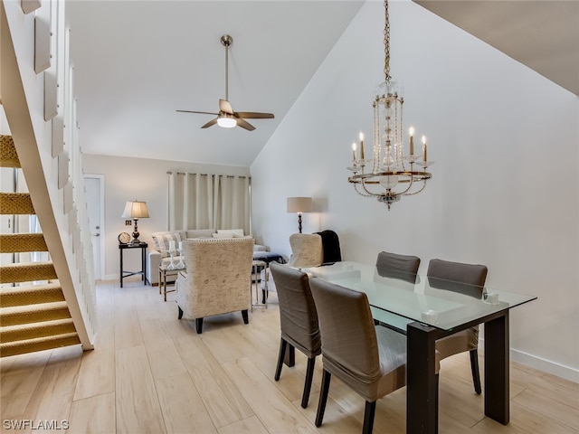 dining space featuring light hardwood / wood-style flooring, high vaulted ceiling, and ceiling fan with notable chandelier