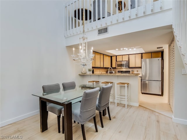 dining room with a chandelier, sink, and light wood-type flooring