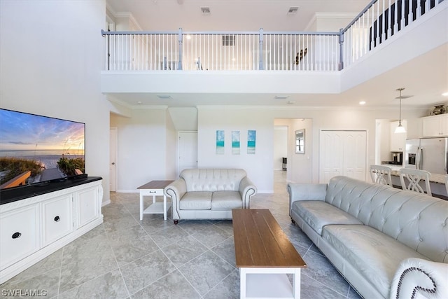 living room with light tile floors, crown molding, and a towering ceiling