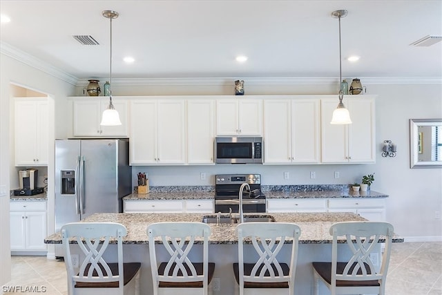 kitchen featuring hanging light fixtures, stainless steel appliances, a kitchen island with sink, and white cabinetry