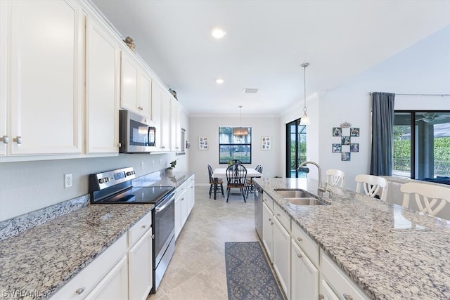 kitchen with sink, hanging light fixtures, appliances with stainless steel finishes, light tile flooring, and white cabinetry