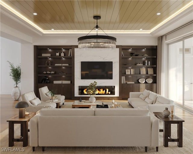 living room with wooden ceiling, a premium fireplace, a tray ceiling, built in shelves, and a wealth of natural light