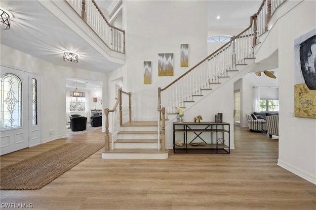 foyer entrance featuring wood-type flooring and a towering ceiling