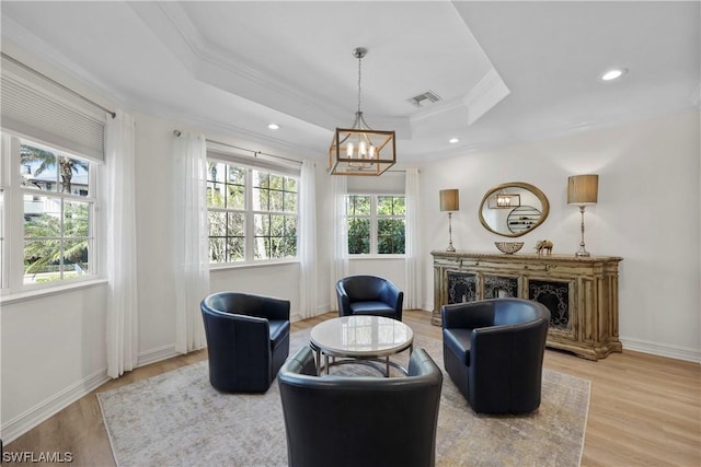 sitting room featuring a tray ceiling, hardwood / wood-style flooring, a notable chandelier, and ornamental molding