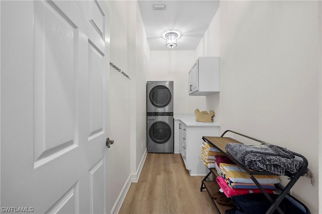 laundry room featuring stacked washer and dryer and light hardwood / wood-style flooring