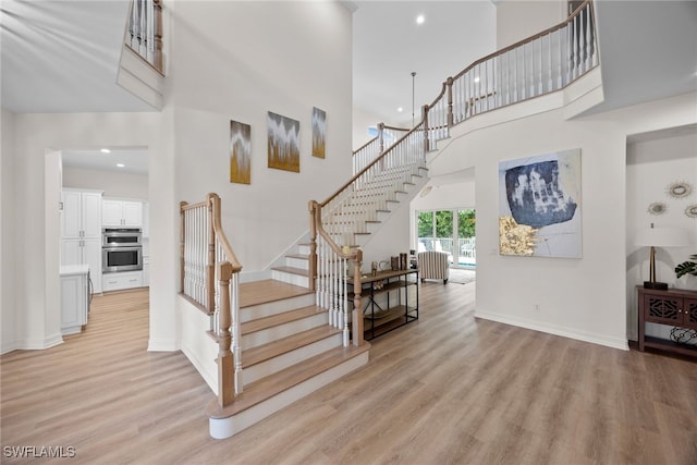 stairs featuring hardwood / wood-style floors and a high ceiling