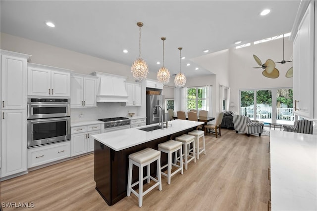 kitchen with pendant lighting, premium range hood, sink, a kitchen bar, and stainless steel appliances