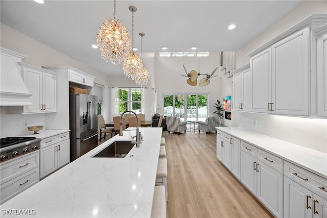 kitchen with white cabinetry, sink, hanging light fixtures, and appliances with stainless steel finishes