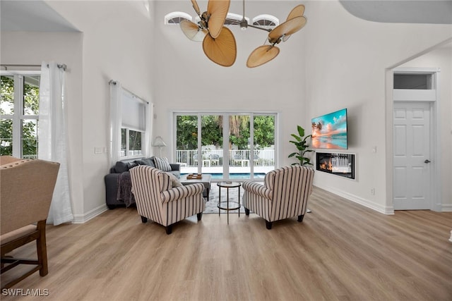 living room featuring a high ceiling, light hardwood / wood-style floors, and ceiling fan