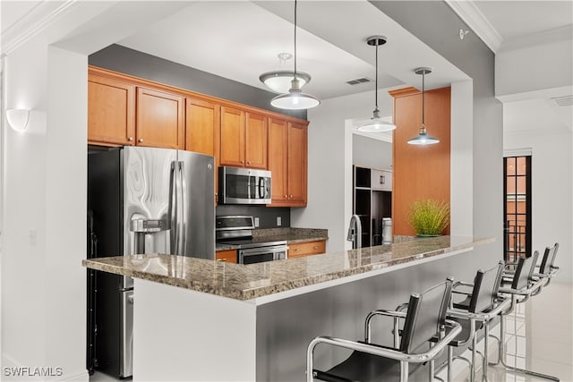 kitchen featuring kitchen peninsula, appliances with stainless steel finishes, a kitchen breakfast bar, decorative light fixtures, and stone counters