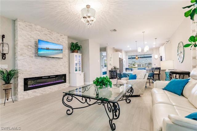 living room featuring light hardwood / wood-style floors, a fireplace, and a chandelier