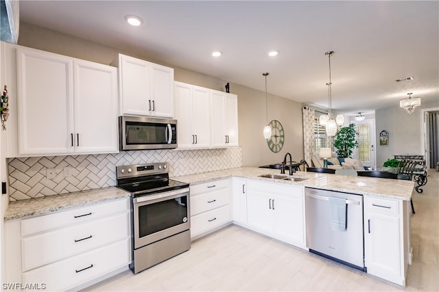 kitchen featuring an inviting chandelier, appliances with stainless steel finishes, decorative light fixtures, and kitchen peninsula