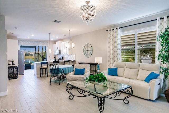 living room featuring sink, a notable chandelier, and light hardwood / wood-style floors