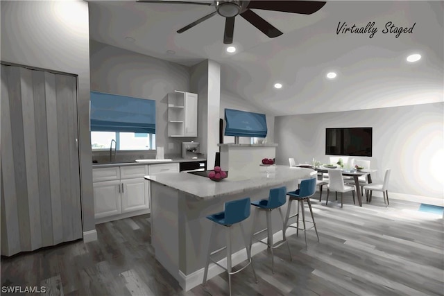 kitchen featuring lofted ceiling, dark hardwood / wood-style flooring, a kitchen island, a kitchen bar, and white cabinetry