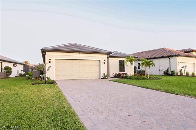 view of front of property featuring central air condition unit, a front yard, and a garage