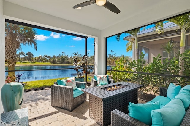 view of patio / terrace with an outdoor living space with a fire pit, ceiling fan, and a water view