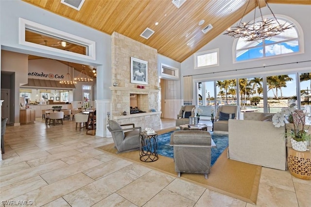 living room with an inviting chandelier, wood ceiling, a stone fireplace, and plenty of natural light