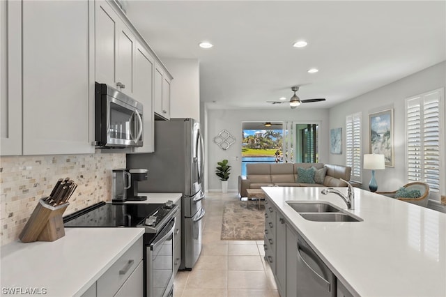 kitchen with sink, light tile patterned floors, ceiling fan, stainless steel appliances, and decorative backsplash