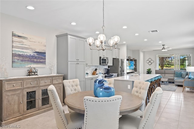 dining area with light tile patterned flooring, sink, and ceiling fan with notable chandelier