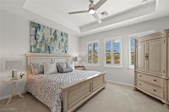 bedroom featuring light carpet, a tray ceiling, and ceiling fan