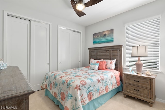 bedroom featuring multiple closets, light colored carpet, and ceiling fan