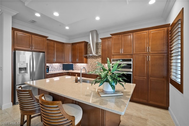 kitchen with light stone countertops, stainless steel appliances, light tile floors, a center island with sink, and wall chimney range hood