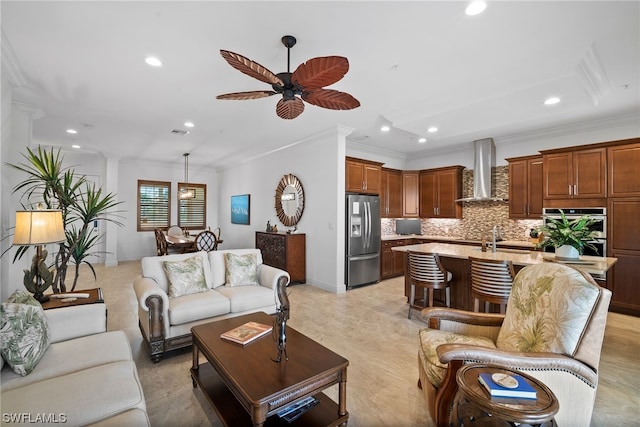 living room with crown molding, light hardwood / wood-style flooring, ceiling fan, and sink