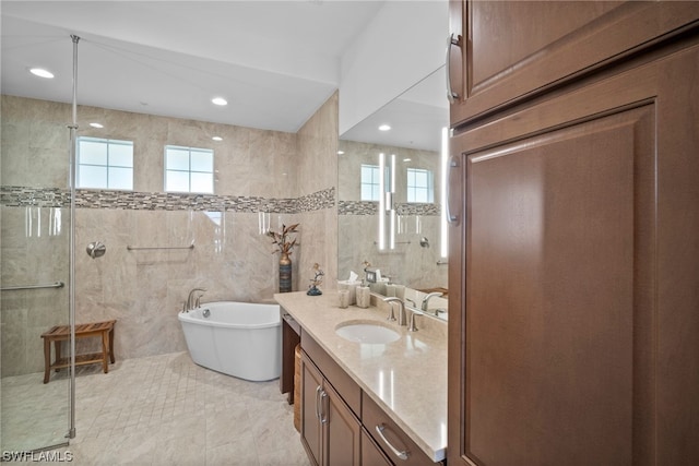 bathroom with tile walls, vanity with extensive cabinet space, tile flooring, and a healthy amount of sunlight