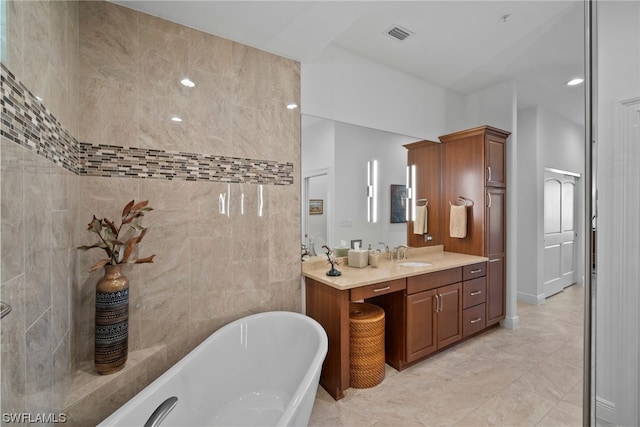 bathroom with tile walls, tile floors, a bathing tub, and vanity