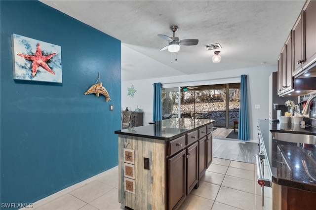 kitchen with dark brown cabinets, light tile patterned floors, and a kitchen island with sink