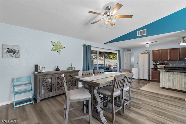 dining space featuring ceiling fan, light wood-type flooring, and vaulted ceiling