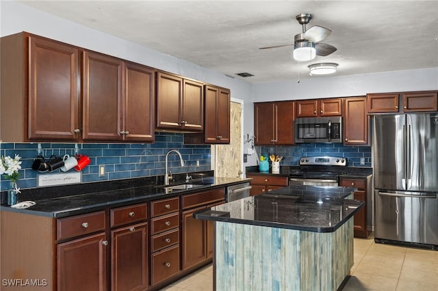 kitchen with sink, decorative backsplash, light tile patterned floors, appliances with stainless steel finishes, and a kitchen island