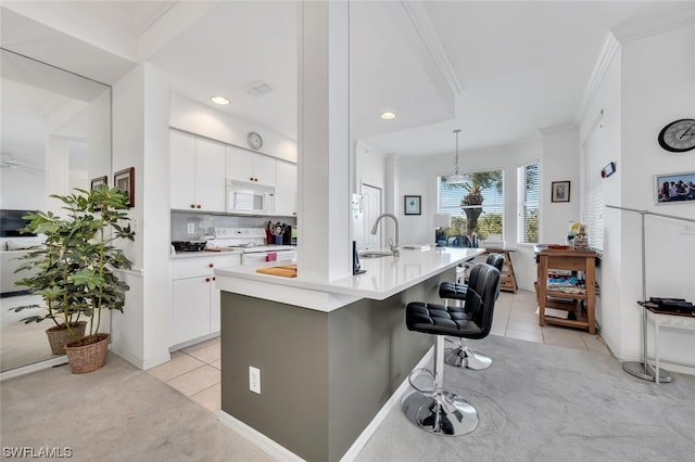 kitchen with a breakfast bar area, a center island with sink, white appliances, and white cabinetry