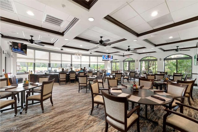 dining space featuring coffered ceiling, ceiling fan with notable chandelier, a wealth of natural light, and light hardwood / wood-style flooring