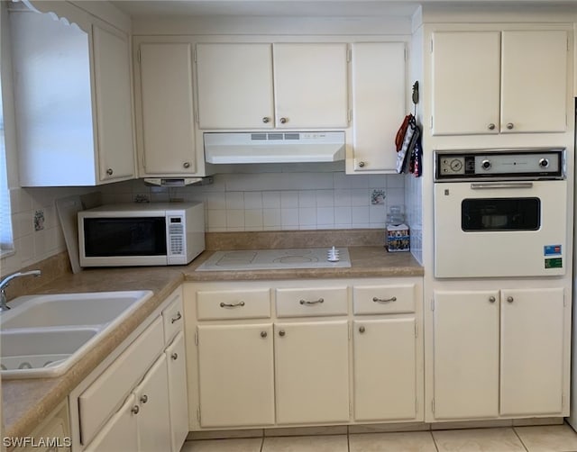 kitchen featuring tasteful backsplash, range hood, white appliances, and sink