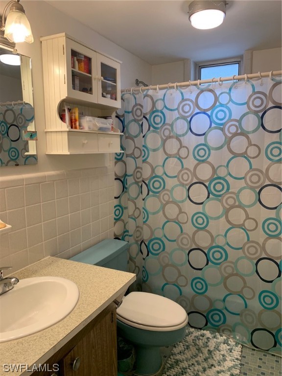 bathroom with vanity, backsplash, toilet, and tile walls