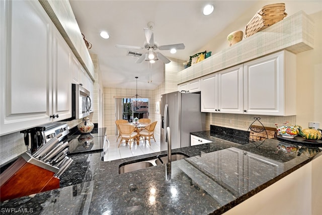 kitchen with dark stone counters, backsplash, white cabinetry, and ceiling fan with notable chandelier